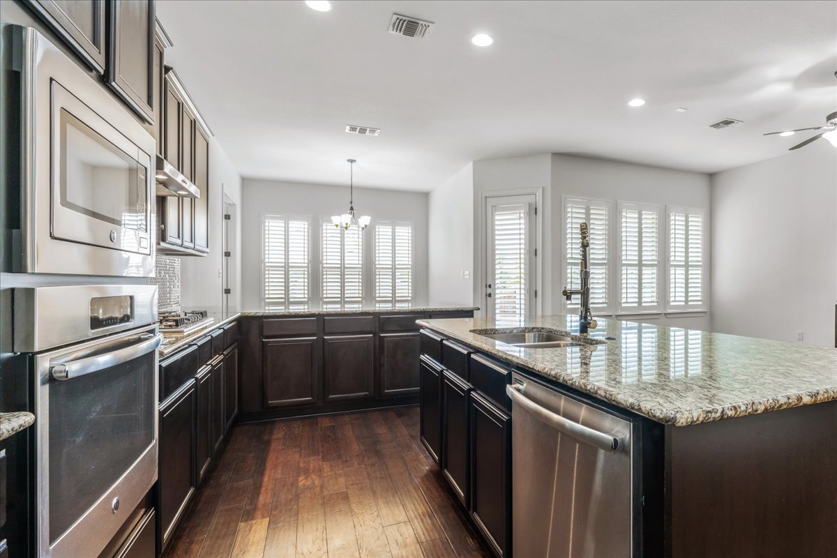 600 Garner Park Drive Georgetown, TX 78628 - Photo 21 of 39 Kitchen with a chandelier, stainless steel appliances, recessed lighting, pendant lighting, and dark brown cabinets