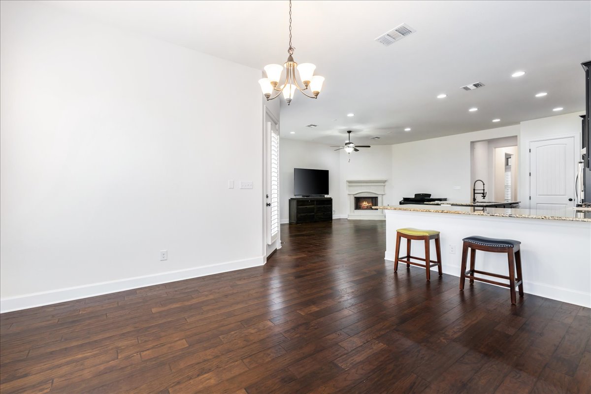 600 Garner Park Drive Georgetown, TX 78628 - Photo 39 of 39 Kitchen featuring light stone countertops, open floor plan, a kitchen breakfast bar, hanging light fixtures, and a warm lit fireplace