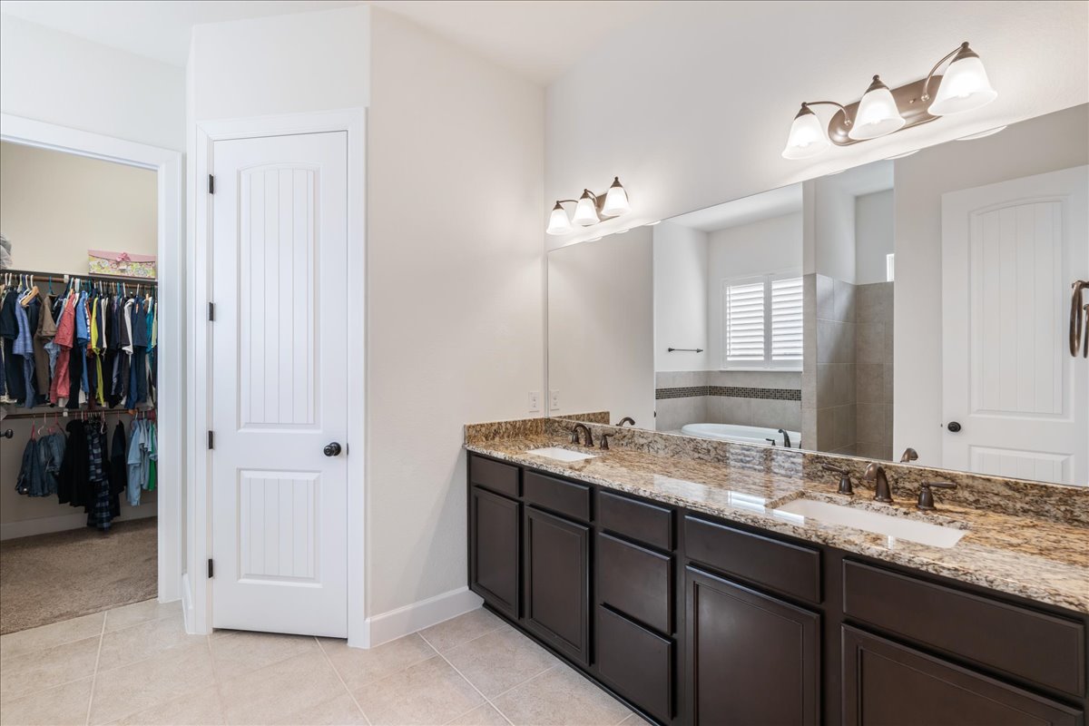 600 Garner Park Drive Georgetown, TX 78628 - Photo 10 of 39 Bathroom featuring double vanity, a walk in closet, light tile patterned flooring, and a tub