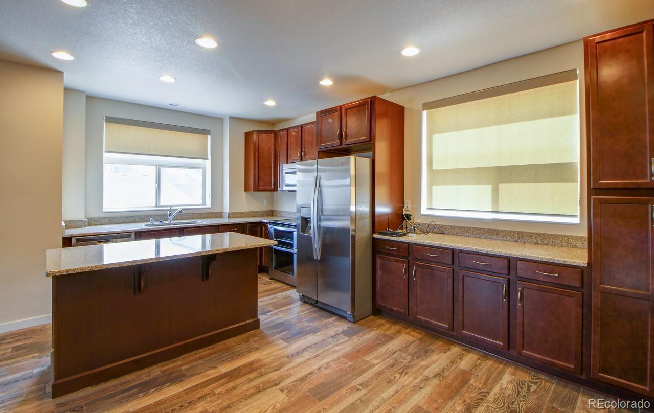10122 Belvedere Loop Lone Tree, CO 80124 - Photo 4 of 17 a kitchen with stainless steel appliances granite countertop a refrigerator a sink dishwasher a stove and a refrigerator with wooden floor