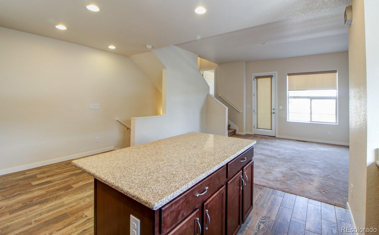 10122 Belvedere Loop Lone Tree, CO 80124 - Photo 6 of 17 a kitchen with kitchen island a sink wooden floor and white appliances