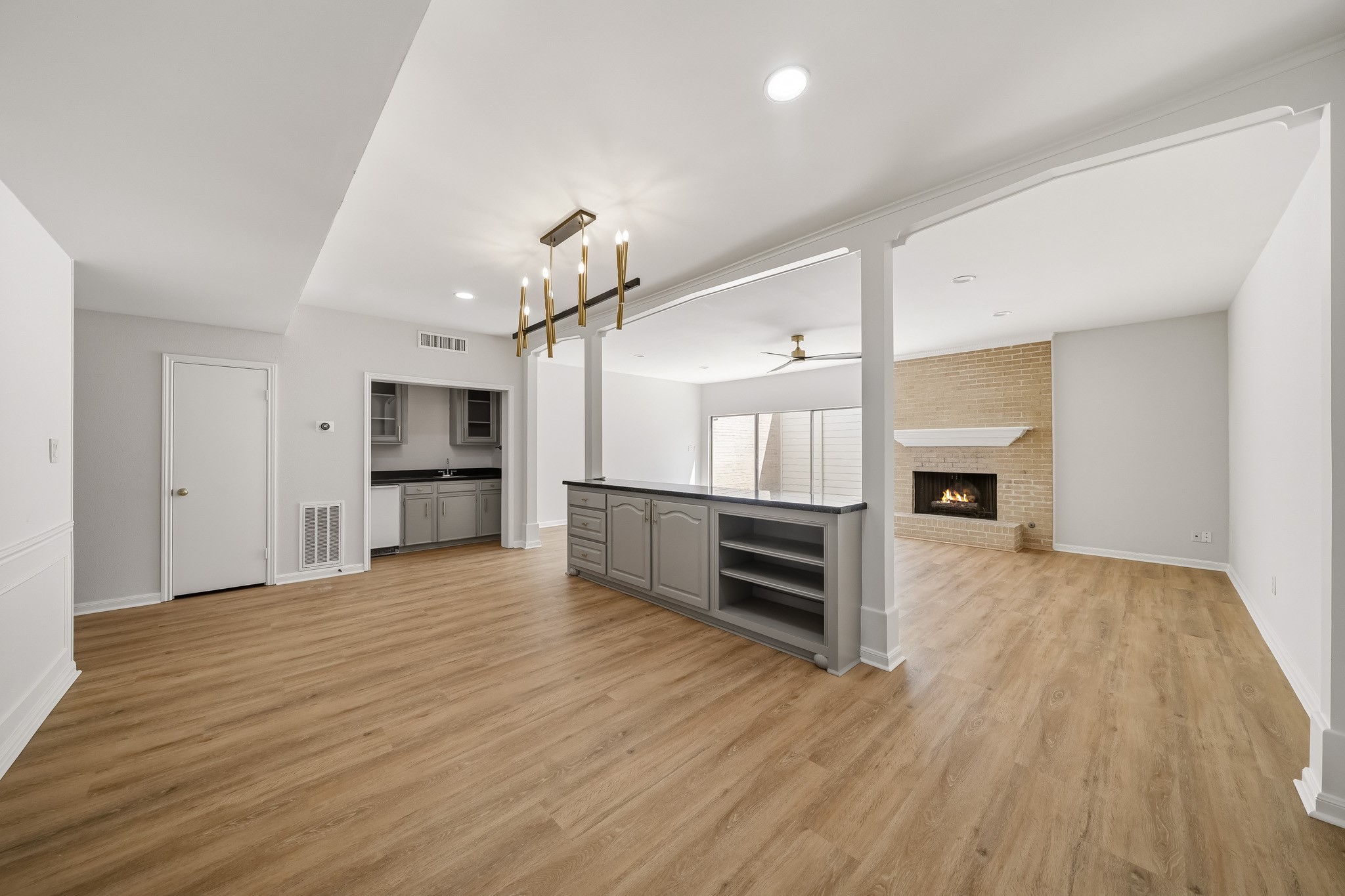 1746 South Gessner Road Houston, TX 77063 - Photo 11 of 25 Spacious open-concept living area with elegant wood flooring, a cozy brick fireplace, and a chic wet bar.