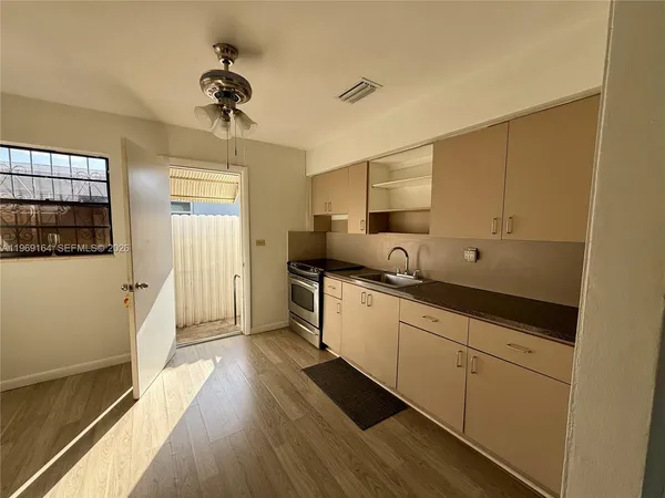 a kitchen with stainless steel appliances a sink stove and wooden floor