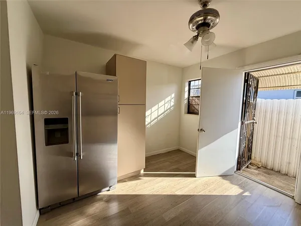 a view of a hallway with a refrigerator and cabinets