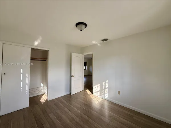 a view of empty room with wooden floor and fan