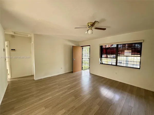 an empty room with wooden floor chandelier and windows