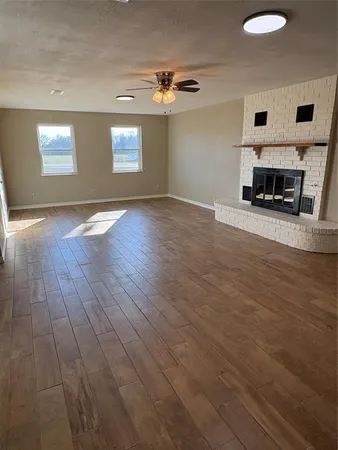 a view of a livingroom with wooden floor and a fireplace