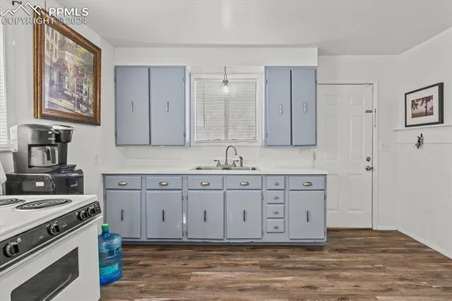 a kitchen with stainless steel appliances granite countertop a stove a sink and a refrigerator with wooden floors