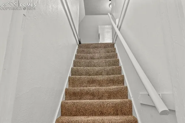 a view of staircase with white walls and white door