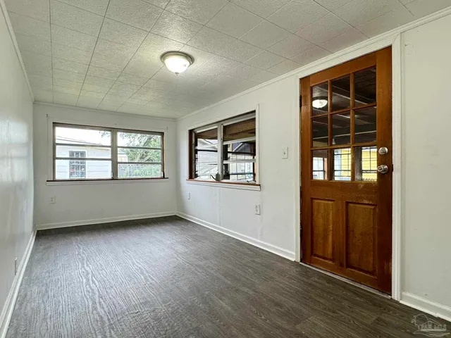 an empty room with wooden floor and windows