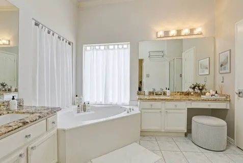 a bathroom with a granite countertop sink a toilet a mirror and bathtub