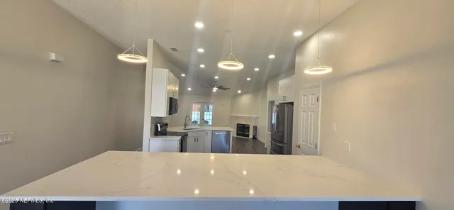 a large kitchen with a refrigerator a sink and a wooden floor