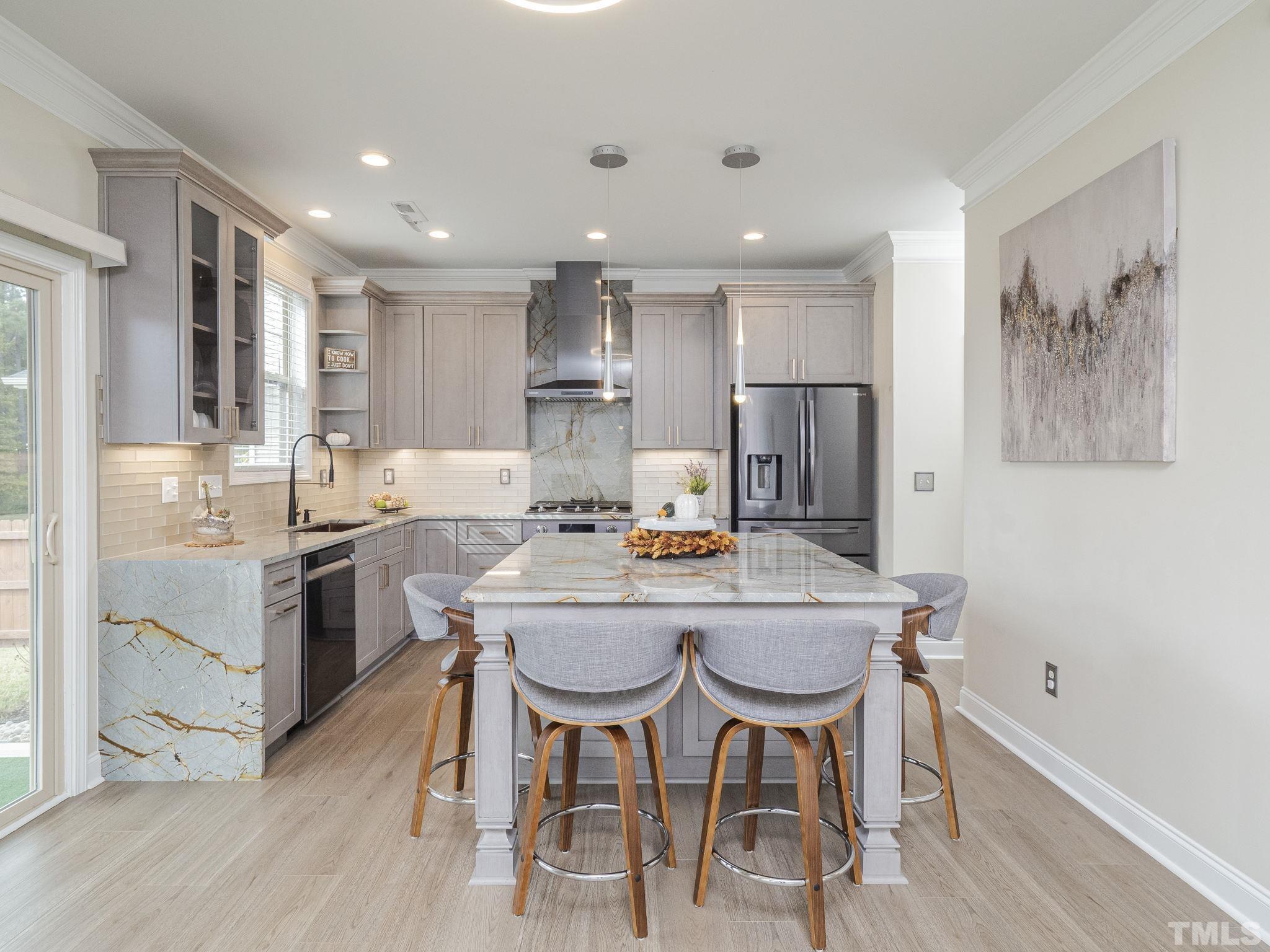 7435 Randshire Way Raleigh, NC 27616 - Photo 21 of 25 a kitchen with kitchen island granite countertop a wooden floor and white stainless steel appliances