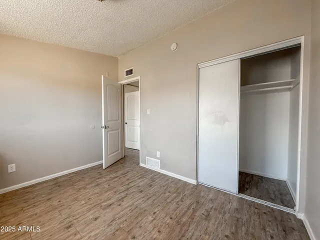 a view of an empty room with wooden floor & closet