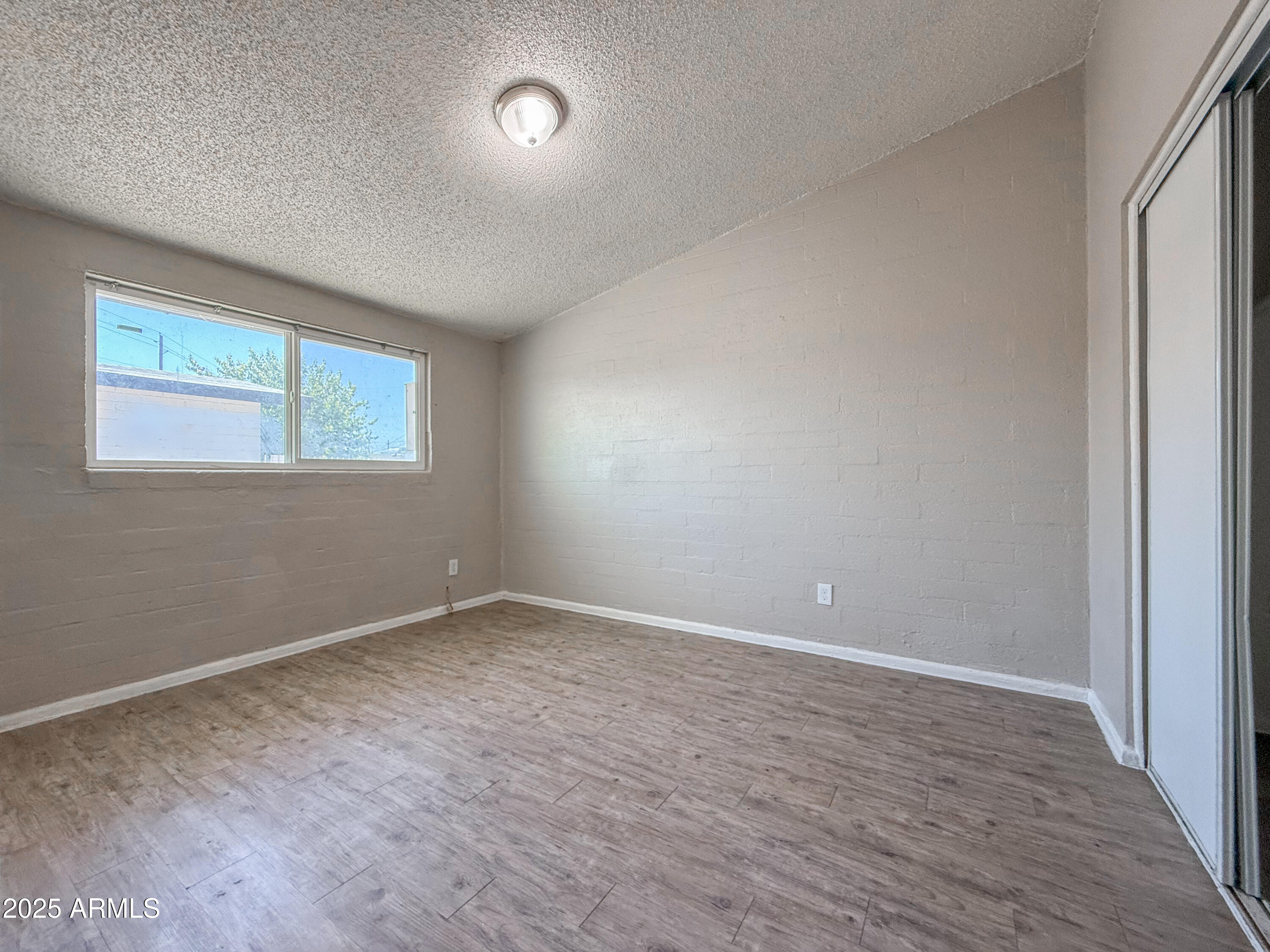 2139 West Devonshire Avenue, Unit 3 Phoenix, AZ 85015 - Photo 10 of 13 a view of an empty room with wooden floor and a window