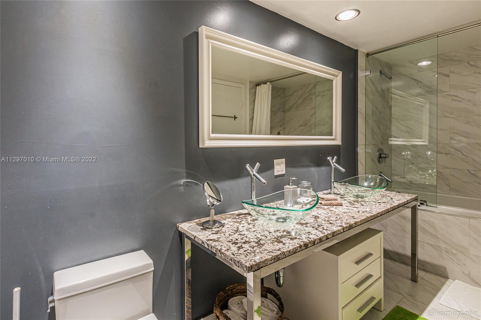 485 Brickell Avenue, Unit 3003 Miami, FL 33131 - Photo 13 of 17 a bathroom with a granite countertop sink a toilet and mirror