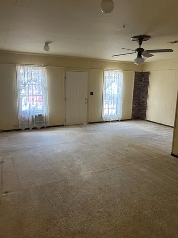 an empty room with windows and fan