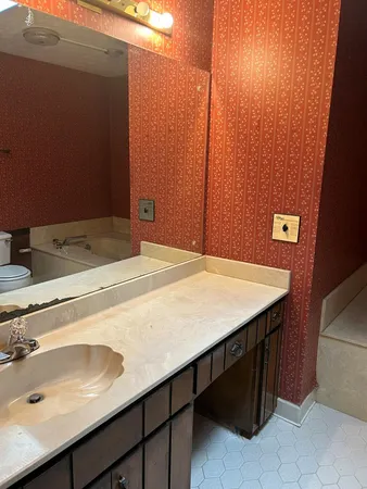 a bathroom with a granite countertop bathtub shower sink vanity and toilet
