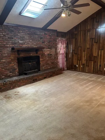 a view of an empty room with a fireplace and a fan