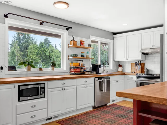 a kitchen with stainless steel appliances white cabinets a sink and a stove