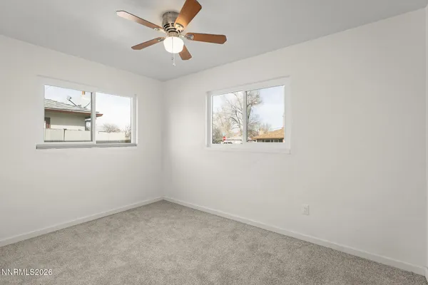 an empty room with windows and fan