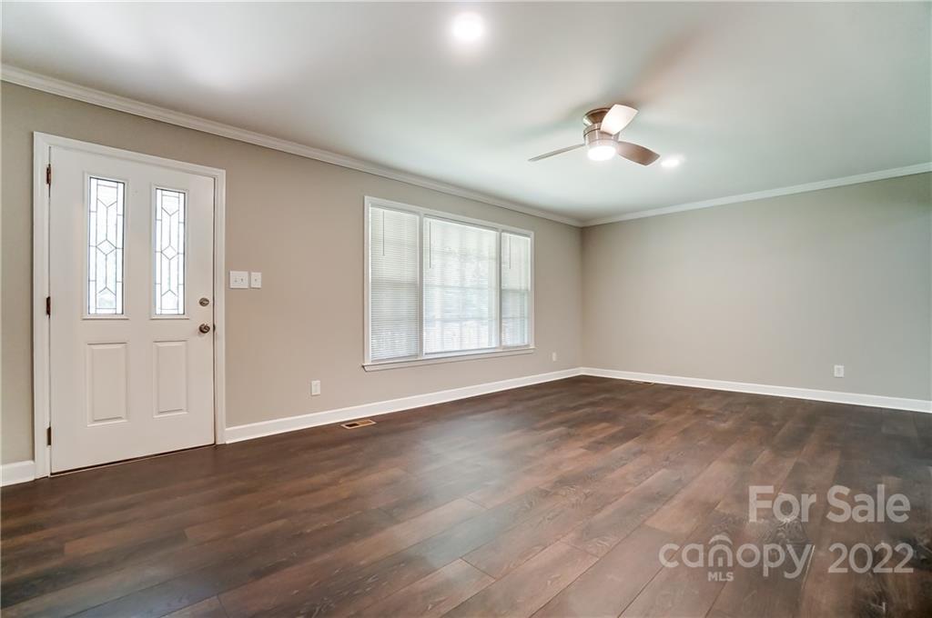 502 Plantation Road Lancaster, SC 29720 - Photo 4 of 44 an empty room with wooden floor chandelier fan and windows