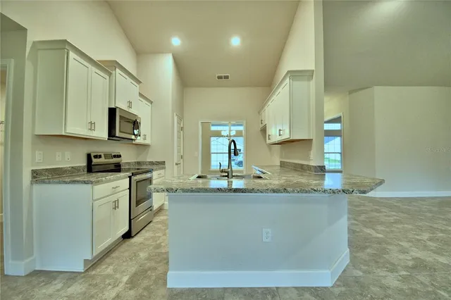 a kitchen with stainless steel appliances granite countertop a stove a microwave and a sink
