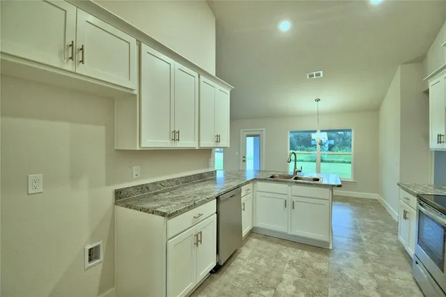 a kitchen with granite countertop a sink stove and cabinets