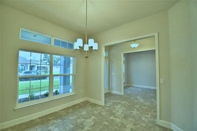 a view of a livingroom with a chandelier fan and kitchen view