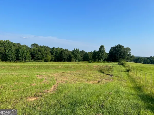a view of a green field with wooden fence