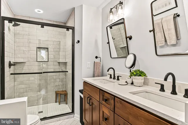 a bathroom with a double vanity sink a mirror a glass door and shower