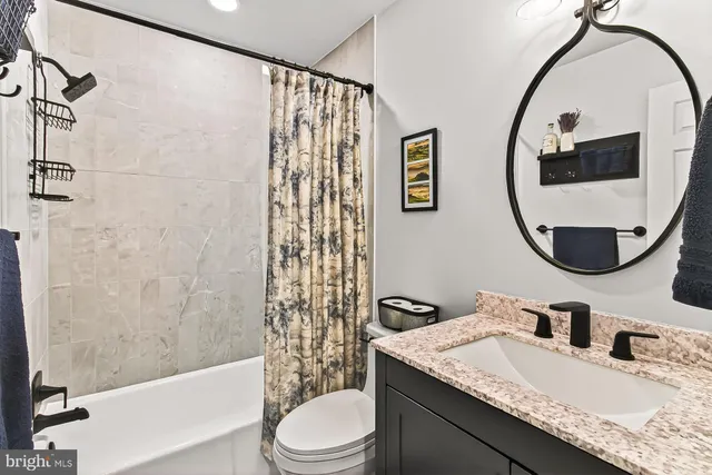 a bathroom with a granite countertop sink mirror vanity and toilet