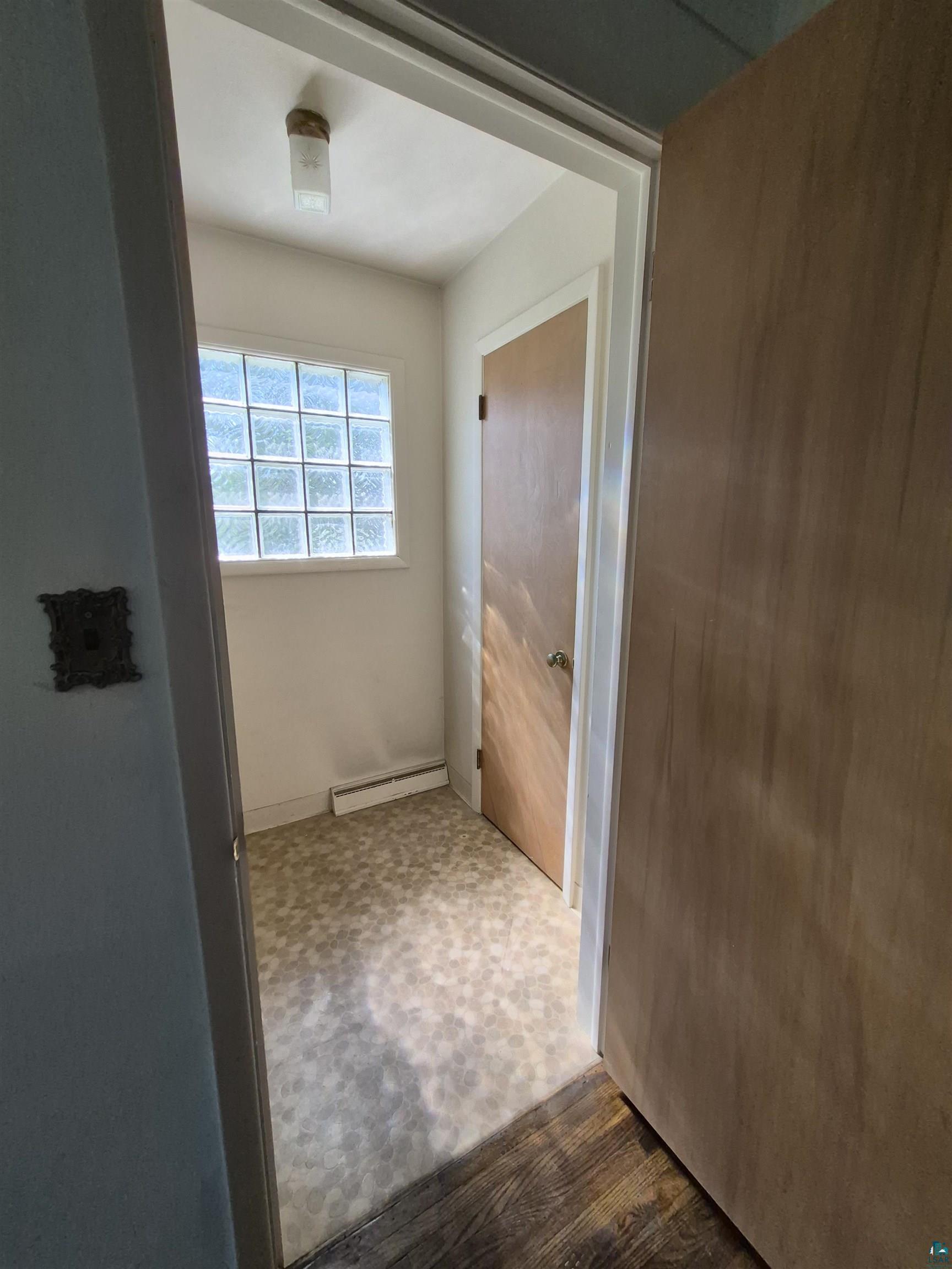 2109 West 22nd Street Duluth, MN 55811 - Photo 8 of 29 White wall paneling with a glass block window, patterned flooring, and a flush mount ceiling light fixture with large coat closet.