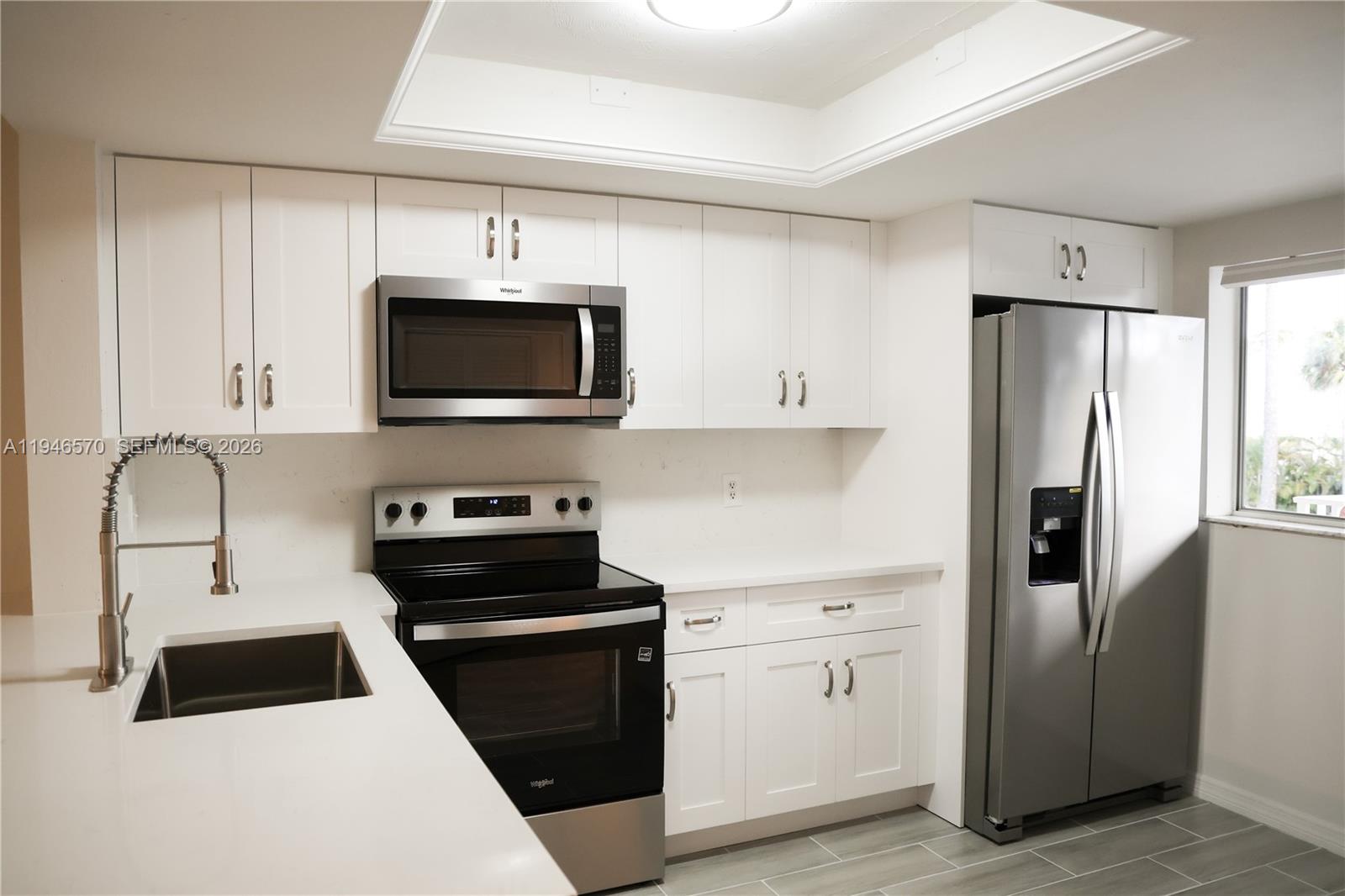 2385 Naples Trace Circle, Unit 5 Naples, FL 34109 - Photo 4 of 13 a kitchen with stainless steel appliances a refrigerator stove and microwave