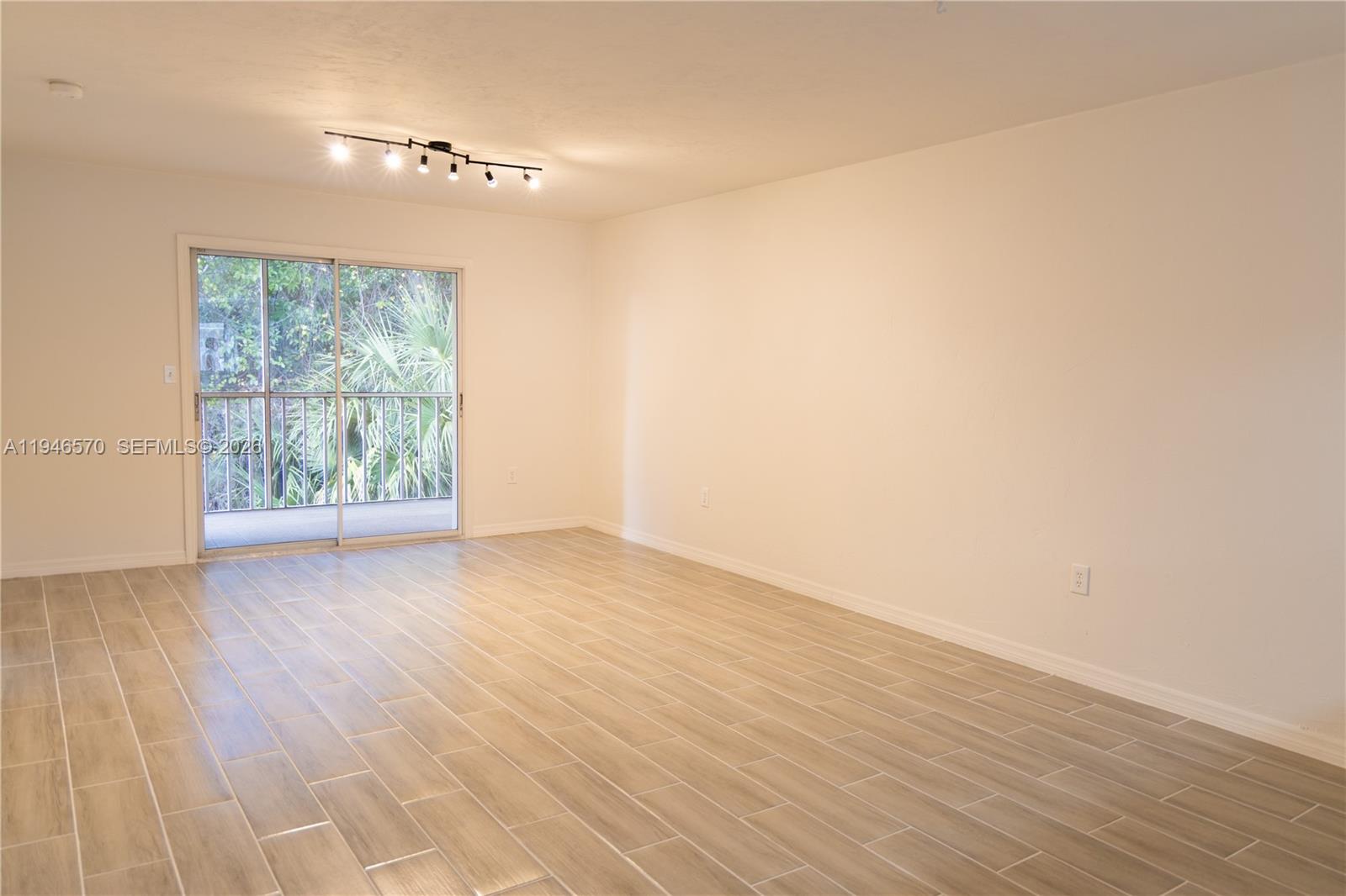 2385 Naples Trace Circle, Unit 5 Naples, FL 34109 - Photo 5 of 13 a view of an empty room with wooden floor and a window