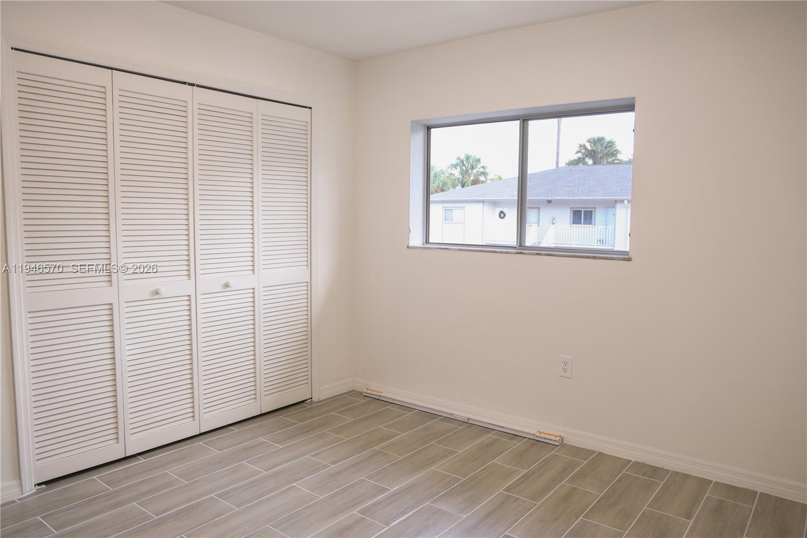 2385 Naples Trace Circle, Unit 5 Naples, FL 34109 - Photo 6 of 13 an empty room with wooden floor and windows
