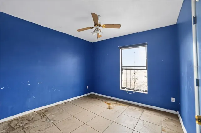 an empty room with windows and fan