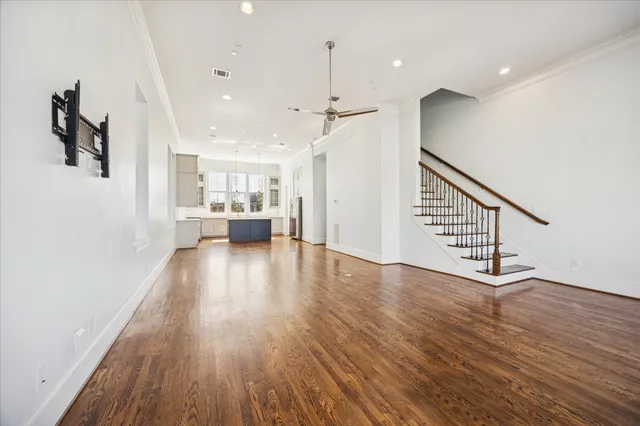 a view of an empty room and kitchen with wooden floor