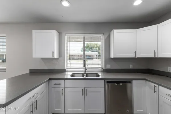 a kitchen with granite countertop white cabinets white appliances and a sink