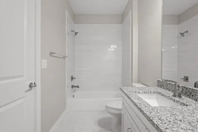 a bathroom with a granite countertop sink a toilet and shower