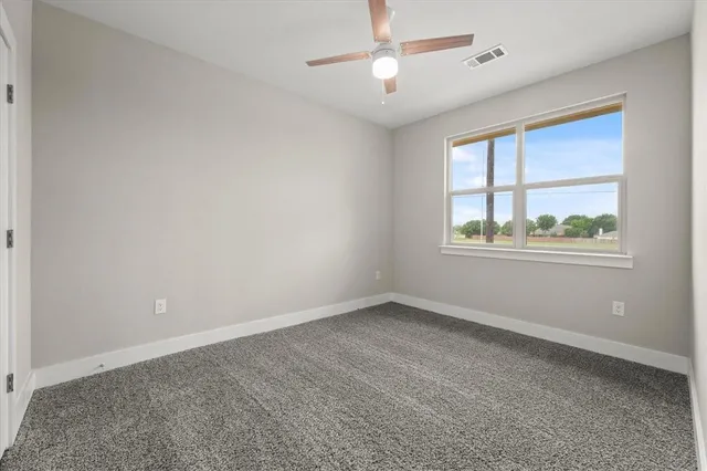 an empty room with a window and ceiling fan