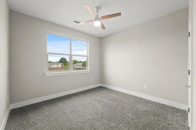 an empty room with windows and ceiling fan