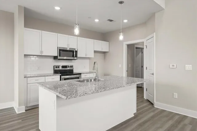 a kitchen with stainless steel appliances granite countertop a sink stove and wooden floor