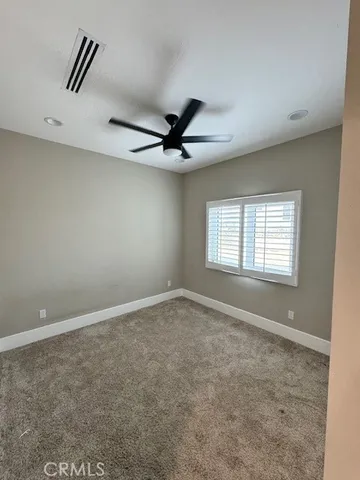 an empty room with ceiling fan and windows