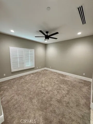 an empty room with windows and ceiling fan