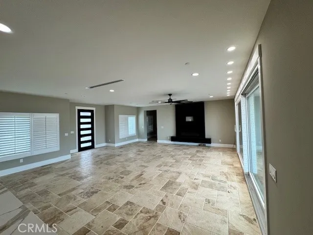 a view of an empty room with window and a kitchen