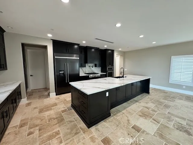 a kitchen with stainless steel appliances granite countertop a sink a stove a refrigerator and a oven