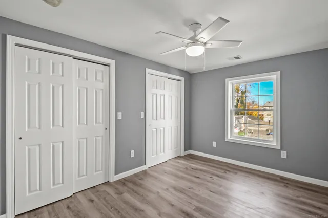 a view of an empty room with wooden floor and window