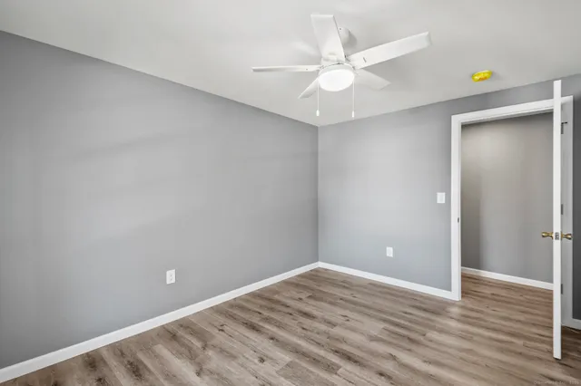 an empty room with wooden floor and fan