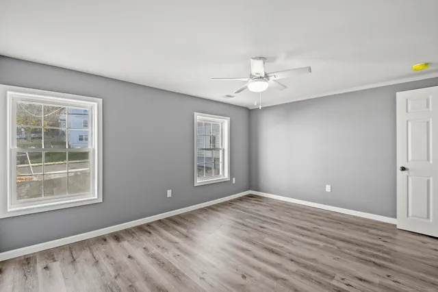 a view of an empty room with a window and wooden floor